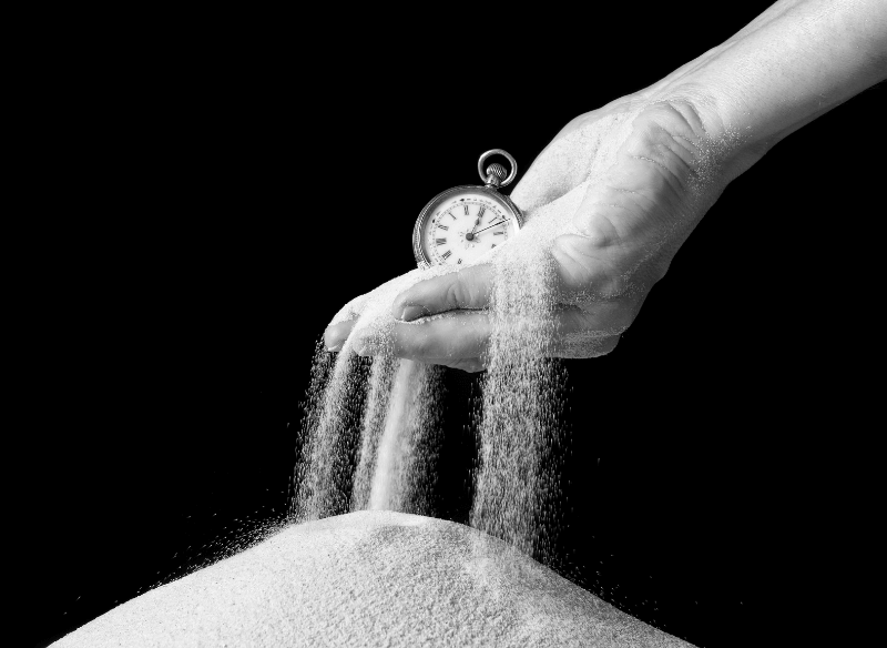 Person holding a clock as the sands of time slip away