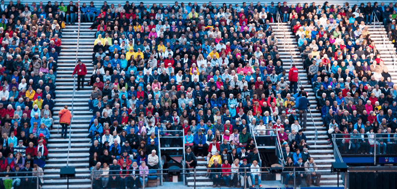 A crowd of people sitting in the bleachers watching a game