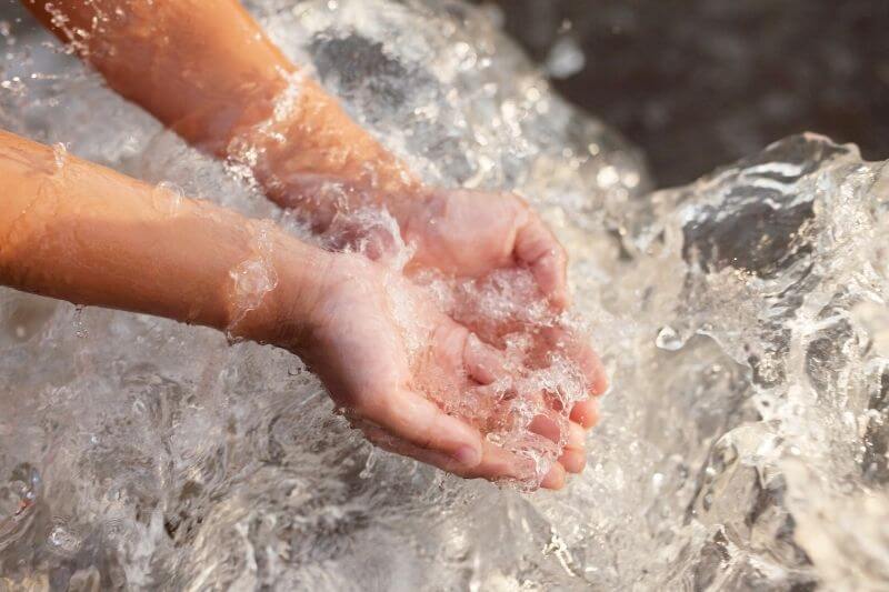 A child’s hands in flowing water, reflecting presence and attention to the moment