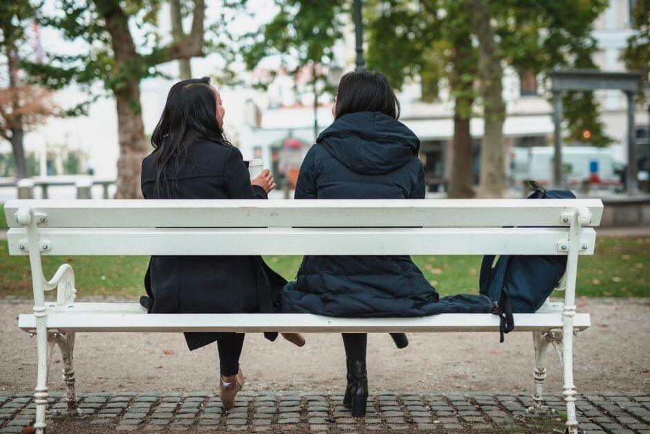 Two women sitting quietly together on a bench at sunset, symbolizing presence without advice.