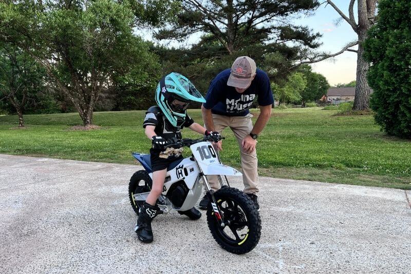 Young rider wearing safety gear while learning to ride a dirt bike.