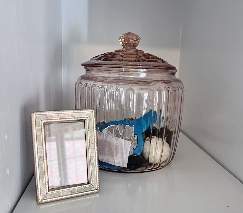 A small empty picture frame resting beside a glass jar, symbolizing openness to change and new possibilities.