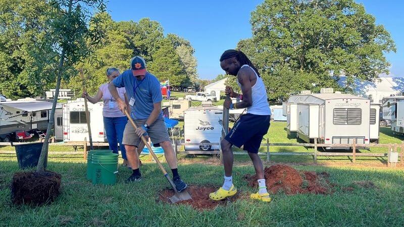 People taking turns digging a hole to plant a tree at the Wild Goose Festival
